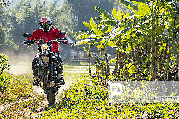 Man riding his scrambler type motorcycle on rugged terrain in Thailand