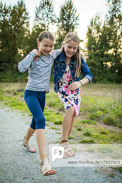 Two girls playfully laugh  touch on the move outside at the park