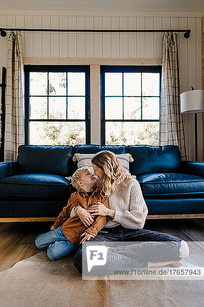 Caucasian mother snuggles with son in cozy cabin