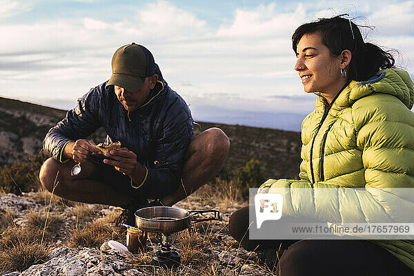 Young couple cooking during a camping trip in the mountains.
