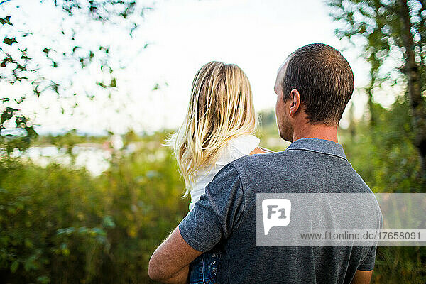 Rear view of attentive father holding his little girl.