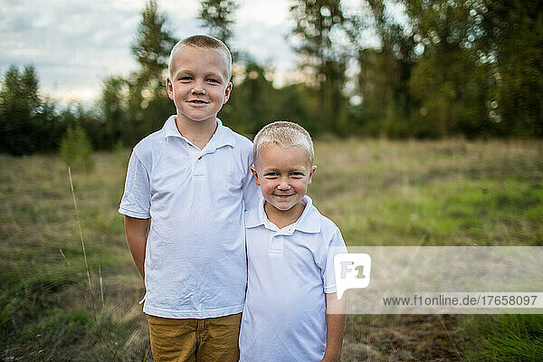 Portrait of two brother standing outdoors in field.