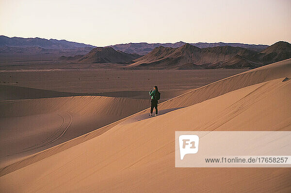 Female taking a photo with phone on a sand dune