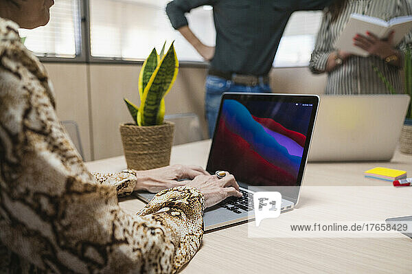 Close up of senior woman hands typing on laptop in an office.