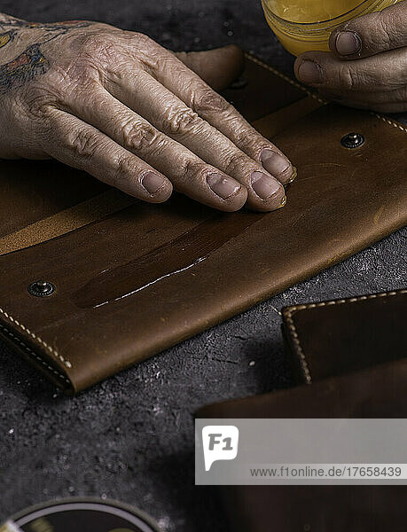 master applies wax to leather wallet. handmade