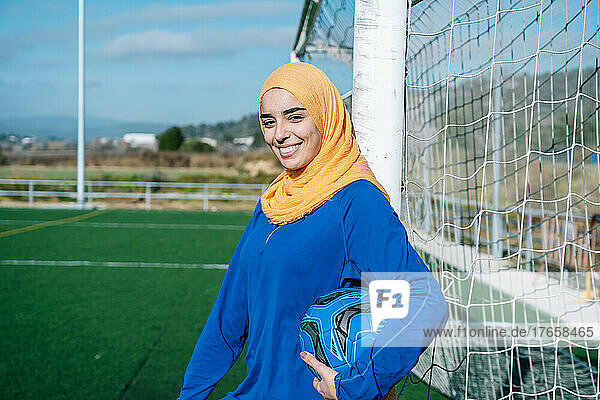 Smiling Arab lady with ball near goal on field