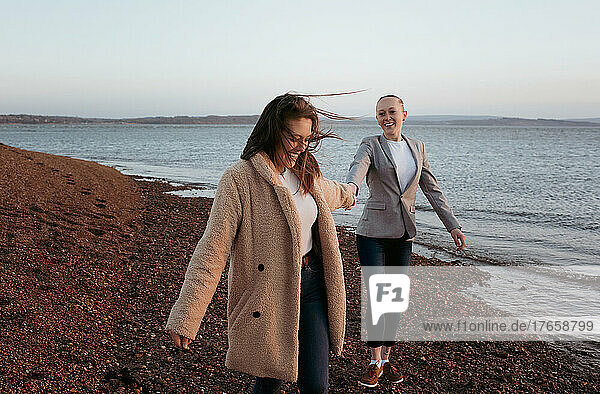 lesbian couple holding hands playfully at the beach