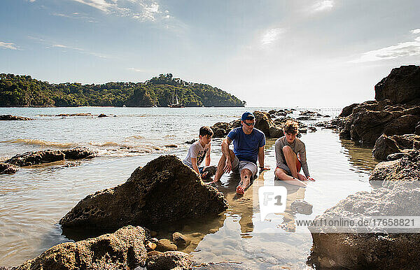Father and sons playing in water on beach on vacation in Costa Rica.