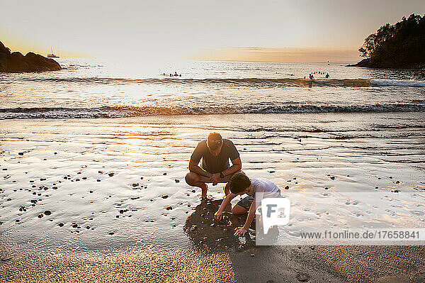 Father and son playing on the beach at sunset in Costa Rica.