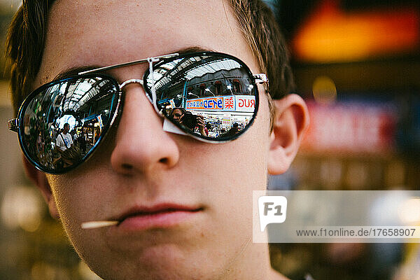 White teenage boy in Asian shopping market wearing sunglasses
