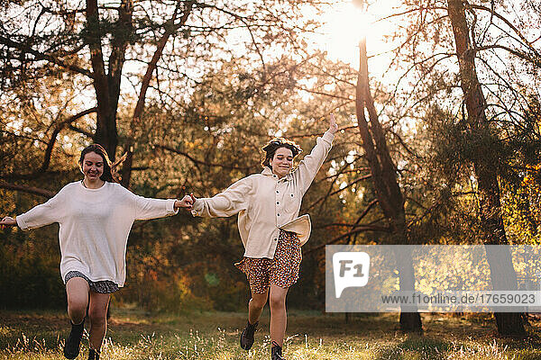 Happy teenage girls running in park holding hands
