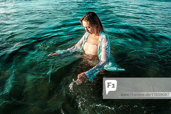 a girl in a shirt enjoys in the ocean on the shore of the Bali island