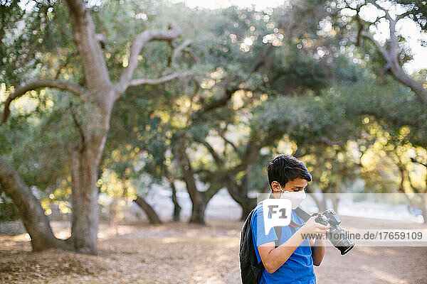 Boy Looking At The Back Of his Camera While Out In Nature