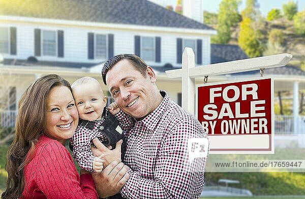 Glückliche junge Familie vor einem Immobilienschild und einem Haus  das zum Verkauf steht