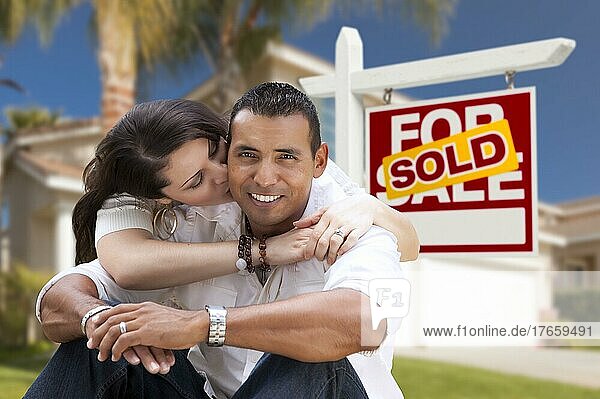 Junge glückliche hispanische junges Paar vor ihrem neuen Haus und verkauft für Verkauf Immobilien Zeichen