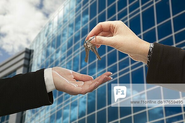 Frau übergibt die Schlüssel an eine andere Frau vor einem Firmengebäude
