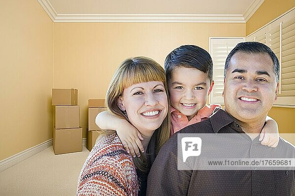 Glückliche junge gemischtrassige Familie in einem Raum mit Umzugskartons