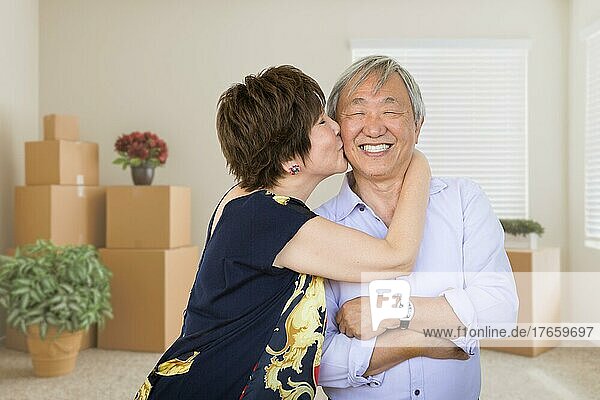 Glückliches älteres chinesisches Paar in einem leeren Raum mit Umzugskartons und Pflanzen