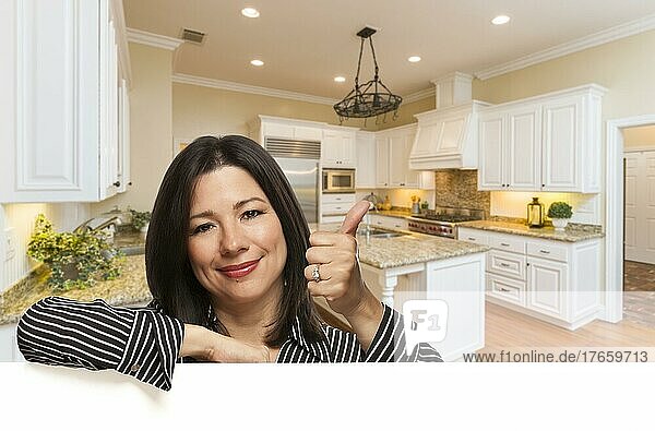 Hispanic Frau mit Daumen nach oben in benutzerdefinierten Küche Interieur lehnt auf weiß