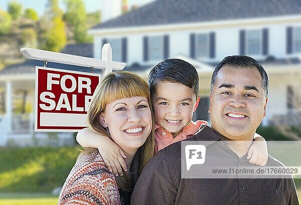 Glückliche junge gemischtrassige Familie vor einem Immobilienschild zum Verkauf und einem neuen Haus