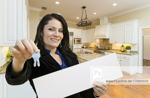 Hübsche hispanische Frau in der Küche mit Hausschlüssel und weißem Schild
