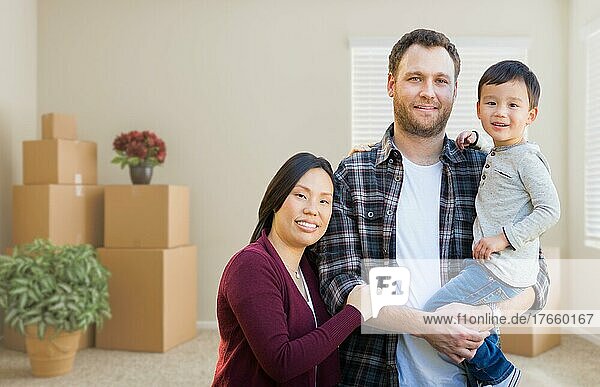 mixed-race chinese and caucasian parents and child inside empty room with moving boxes