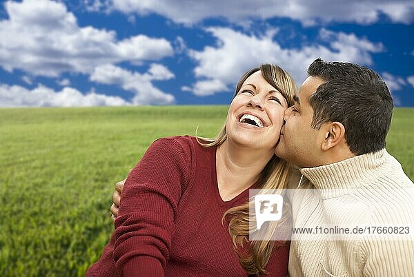 Happy  loving mixed couple sitting in graß field
