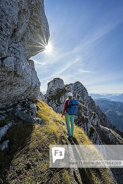 Sonne scheint auf einen Wanderweg mit Wanderin  Blick über Berglandschaft  Nuaracher Höhenweg  Loferer Steinberge  Tirol  Österreich  Europa