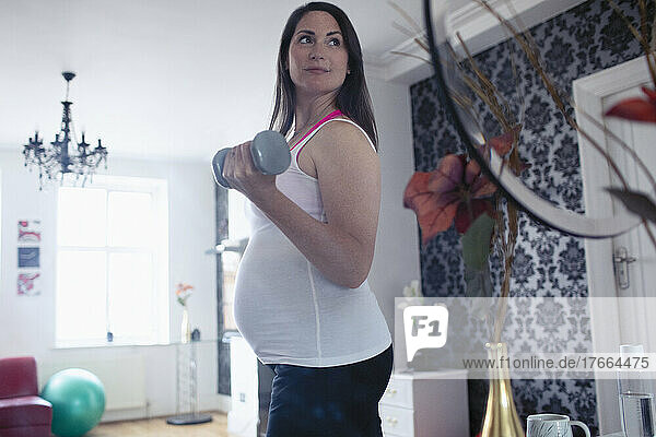 Schwangere Frau mit Hanteln bei der Arbeit zu Hause