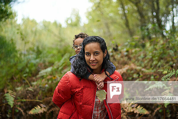 Portrait mother piggybacking son on hike in woods