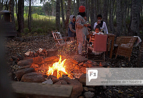 Familie entspannt am Tisch am Lagerfeuer im Wald