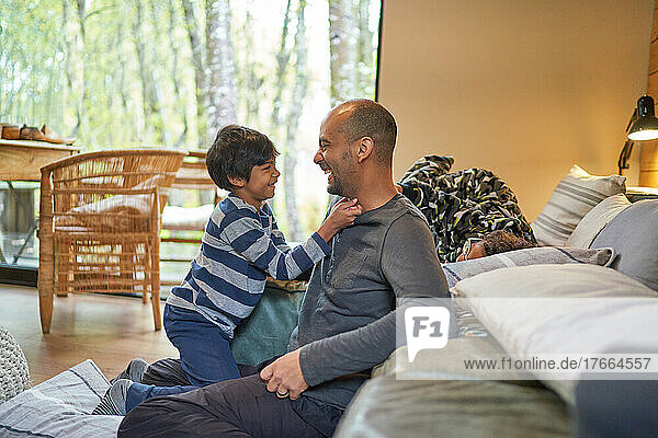 Happy father and son face to face in living room