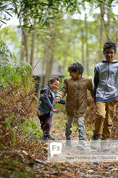 Happy brothers hiking on trail in woods