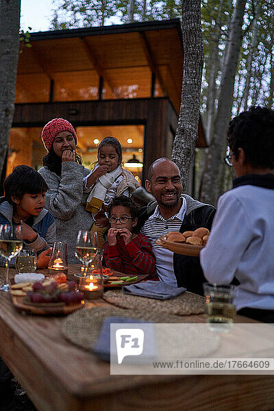 Family eating at table outside cabin