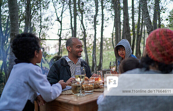 Glückliche Familie beim Essen am Tisch im Wald