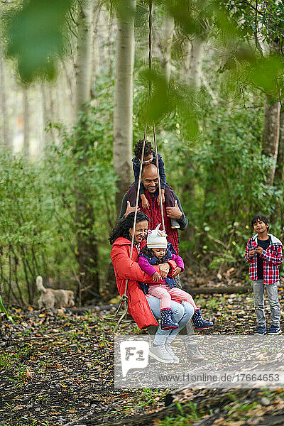 Verspielte Familie auf einer Schaukel im Wald