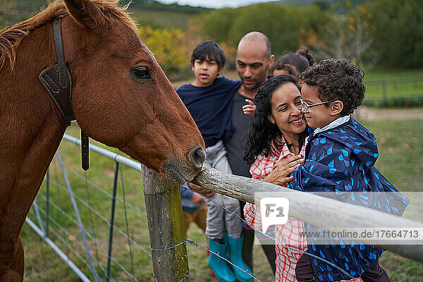Mutter und Sohn betrachten das Pferd am Zaun