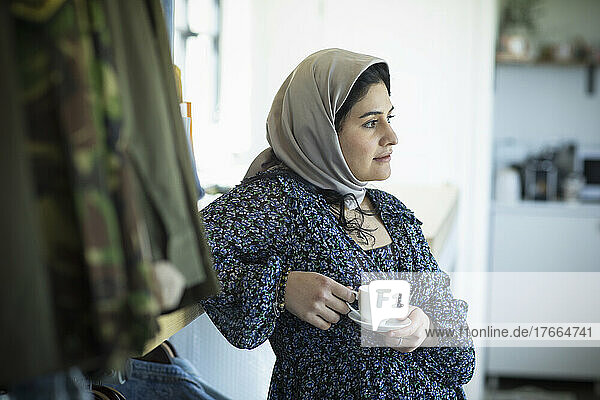 Nachdenkliche junge Muslimin im Hidschab trinkt Kaffee