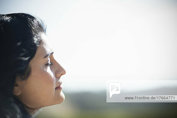 Profil: Gelassene junge Frau  die sich mit geschlossenen Augen im Sonnenlicht sonnt