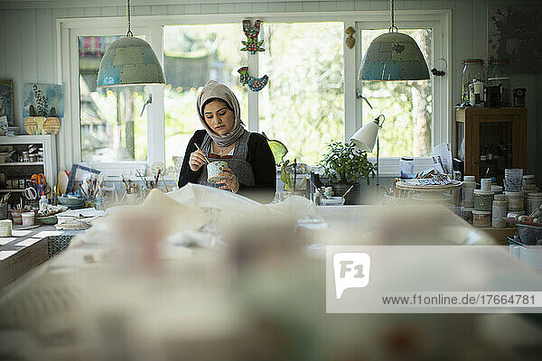 Young female Muslim artist working in art studio