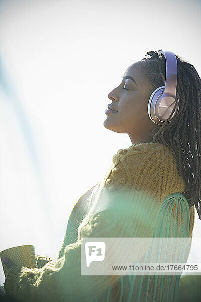 Gelassene junge Frau mit Kopfhörern  die sich im Sonnenschein sonnt