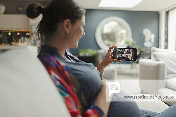Schwangere Frau im Videochat mit Freunden auf dem Bildschirm eines Smartphones