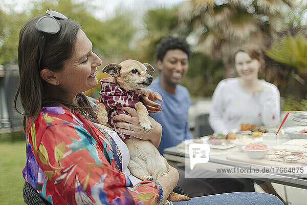 Glückliche Frau mit süßem Hund am Terrassentisch