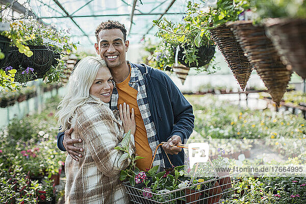 Portrait happy couple shopping for flowers in greenhouse