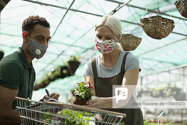 Gärtnereibesitzer mit Gesichtsmasken bei der Arbeit im Gewächshaus