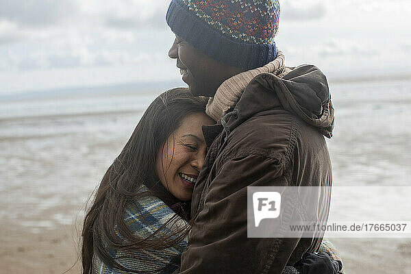 Happy affectionate couple hugging on winter beach