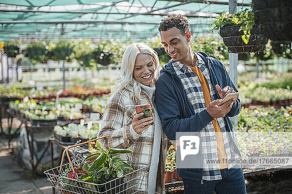 Ehepaar mit Smartphones beim Einkaufen im Gartengeschäft