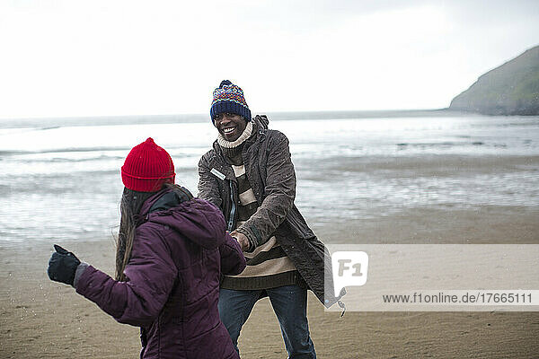 Happy playful couple on wet winter beach