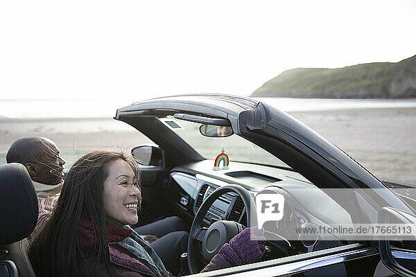 Glückliches Paar fährt Cabrio am Winterstrand