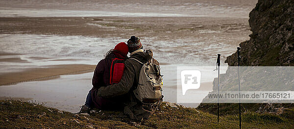 Verliebtes Wandererpaar auf Klippe über Winterstrand